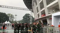 Aparat bersiaga di depan area Stadion Utama Gelora Bung Karno (SUGBK) yang diguyur hujan deras jelang laga FIFA Matchday Timnas Indonesia vs Argentina pada Senin (19/6/2023). (Liputan6.com/Melinda Indrasari)