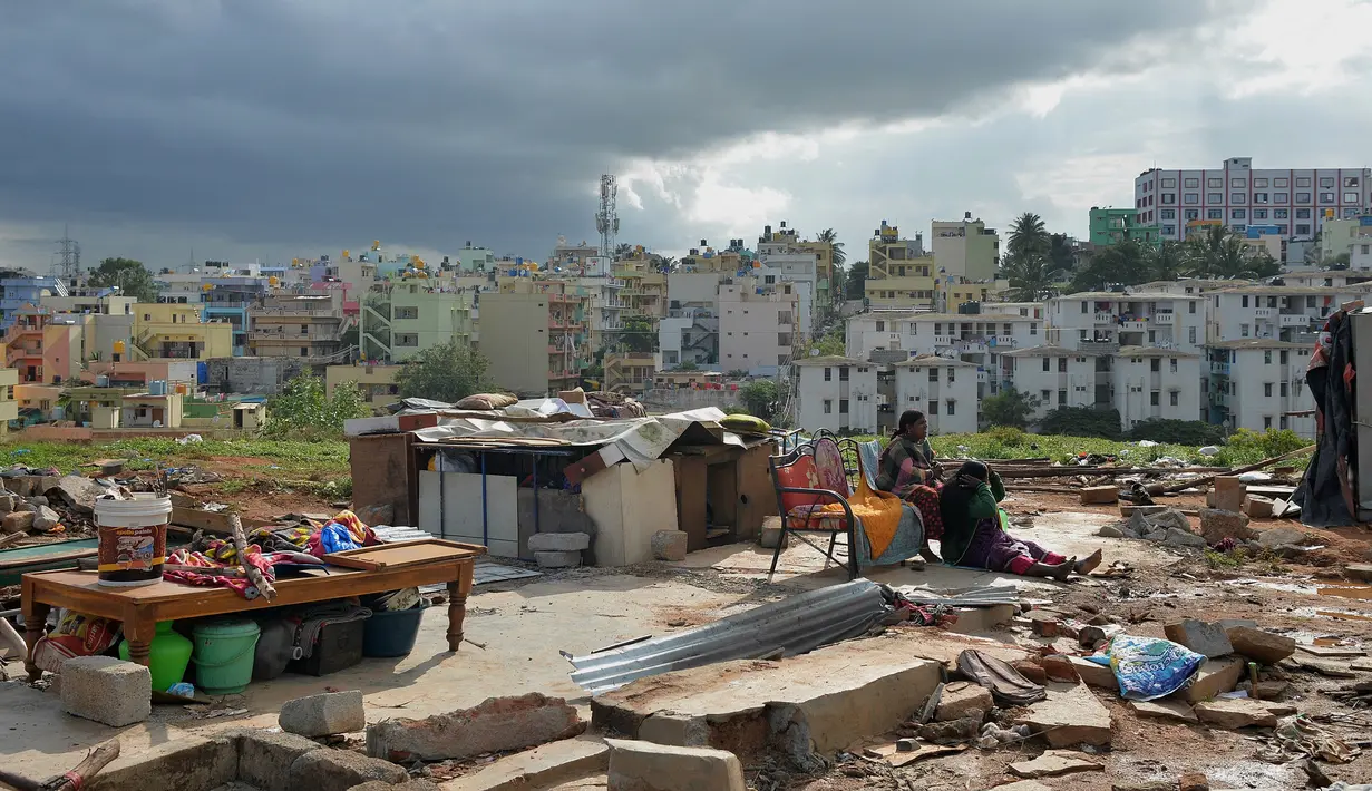 Dua warga duduk di samping puing reruntuhan permukiman kumuh di Banglore, India, 24 Juli 2018. Banyak warga miskin India bermigrasi ke kota-kota besar untuk mencari pekerjaan. (MANJUNATH KIRAN/AFP)
