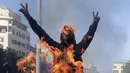 Demonstran antipemerintah meneriakkan slogan-slogan dekat kobaran api saat protes menentang elite penguasa di Kota Jal el-Dib, Lebanon, Selasa (14/1/2020). Demonstran menganggap elite penguasa gagal mengatasi ekonomi yang menurun tajam. (AP Photo/Hassan Ammar)