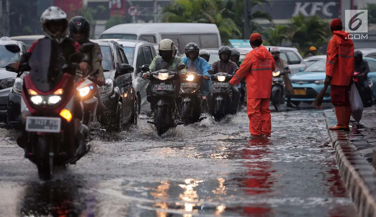 Sejumlah kendaraan melintasi genangan air usai hujan deras dikawasan Tugu Tani, Jakarta, Kamis (12/10). Agar tidak terjadi genangan kembali petugas dari Dinas Kebersihan membuang aliran air hujan kedalam selokan. (Liputan6.com/Faizal Fanani)
