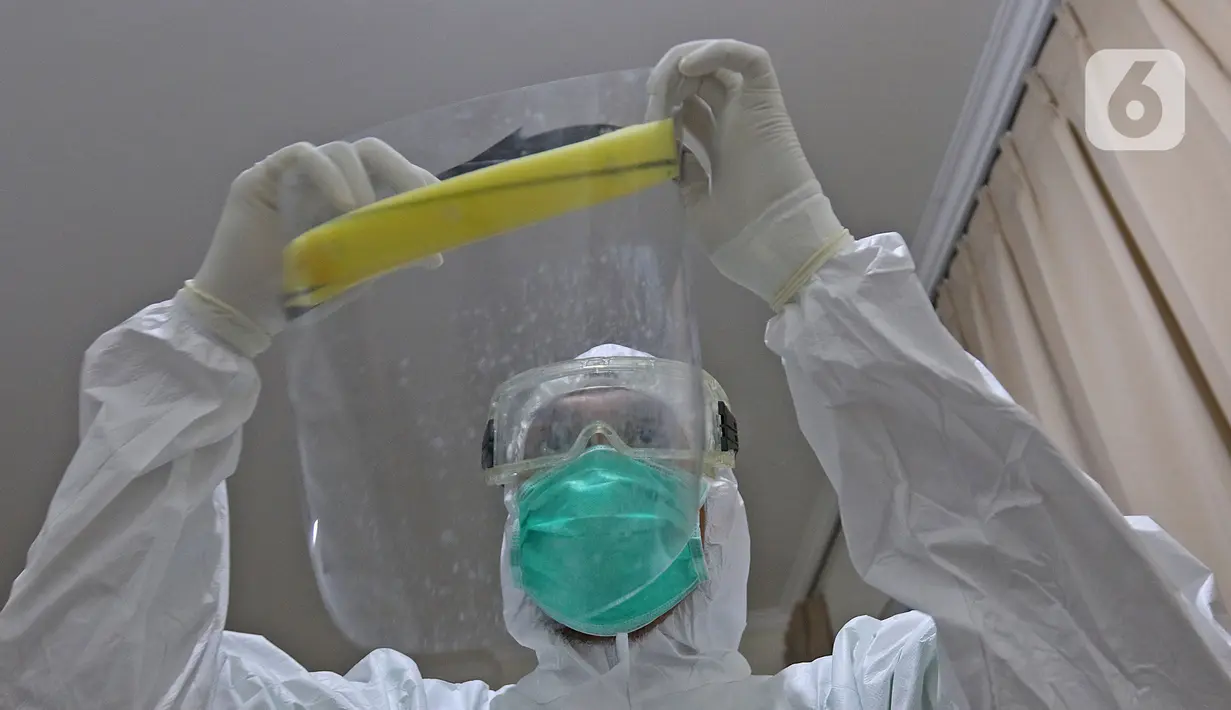 dr Rahmadi Iwan Guntoro, Sp.P bersiap memakai face shield atau pelindung wajah di Rumah Sakit Haji, Jakarta, Kamis (9/4/2020). Gugus Tugas Percepatan Penanganan COVID-19 telah mengeluarkan rekomendasi standar APD berdasarkan tiga tingkatan perlindungan. (Liputan6.com/Herman Zakharia)