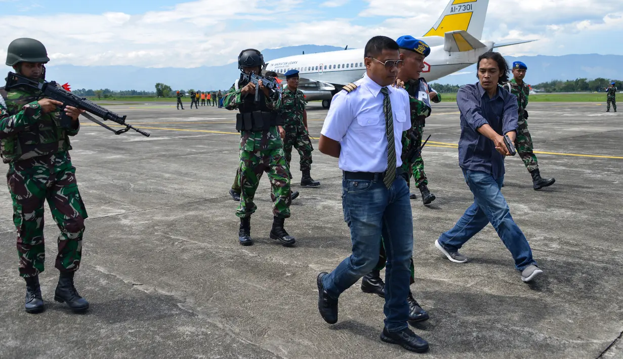 Sejumlah personel TNI AU membawa pilot yang ditahan saat latihan serangan pesawat di Lanud Sultan Iskandar Muda, Blang Bintang, Provinsi Aceh, Kamis (19/2/2020). (CHAIDEER MAHYUDDIN/AFP)