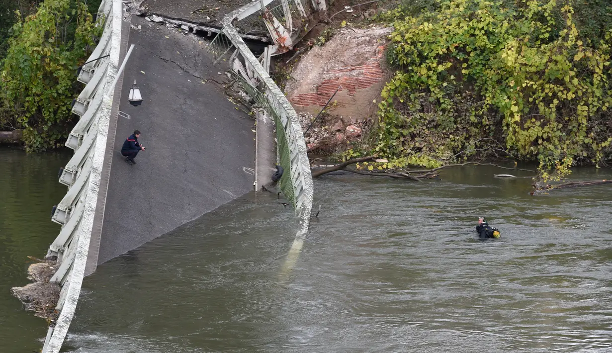 Tim penyelamat menyelam di  sungai Tarm, dekat jembatan gantung yang ambruk di Prancis, Selasa (18/11/2019). Satu mobil dan satu truk dan kemungkinan sebuah kendaraan lainnya yang sedang melintasi jembatan itu langsung hanyut ke sungai. (ERIC CABANIS/AFP)