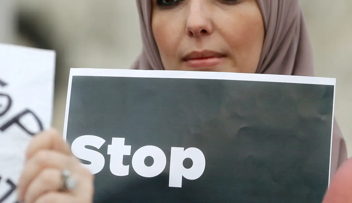 Seorang wanita membawa poster saat berunjuk rasa di pusat kota Miami, AS, Kamis (26/1). Pengunjuk rasa menolak kebijakan Presiden AS, Donald Trump yang membatasi warga Muslim masuk ke AS. (AP Photo / Alan Diaz)