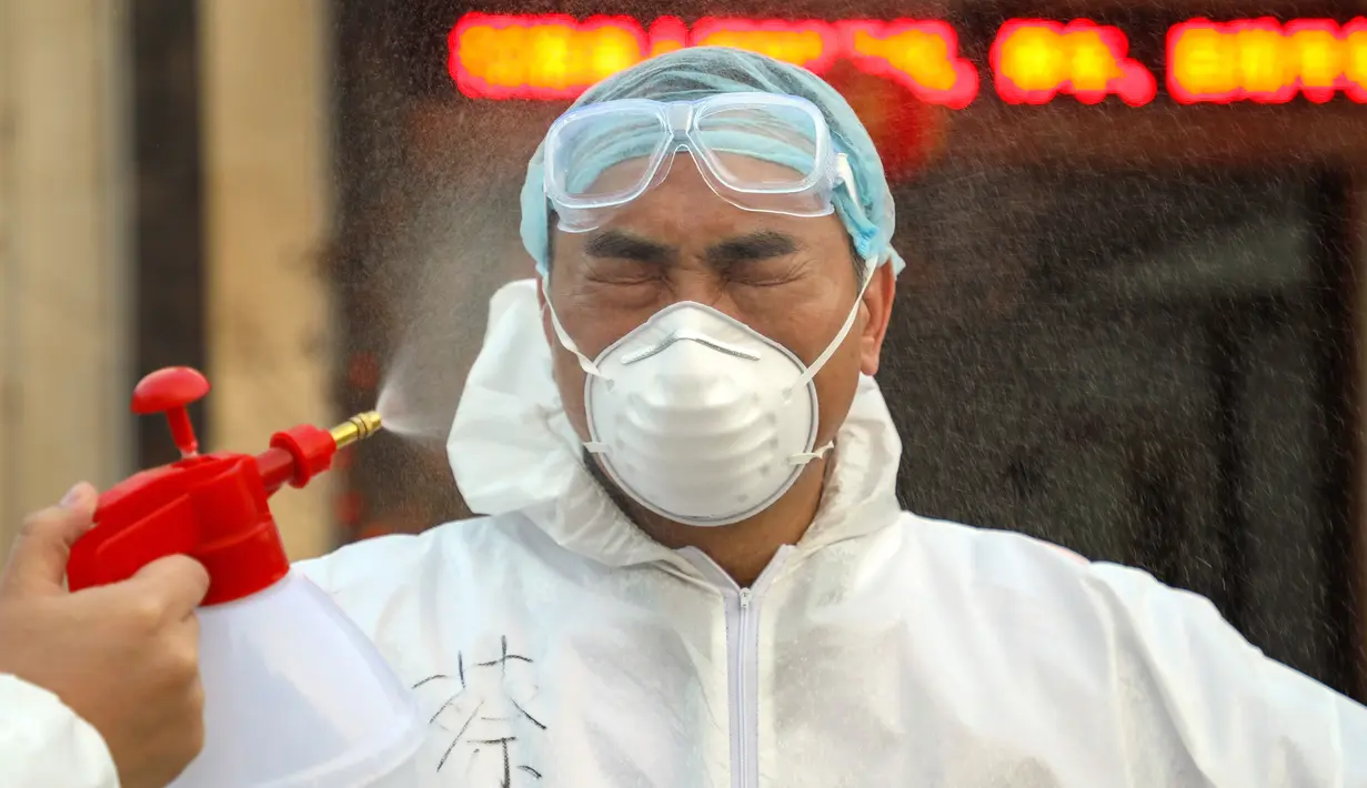 Pekerja berpakaian pelindung didesinfeksi di luar hotel yang digunakan dalam isolasi medis virus corona di Wuhan, Provinsi Hubei, China, Senin (3/2/2020). (Chinatopix via AP)