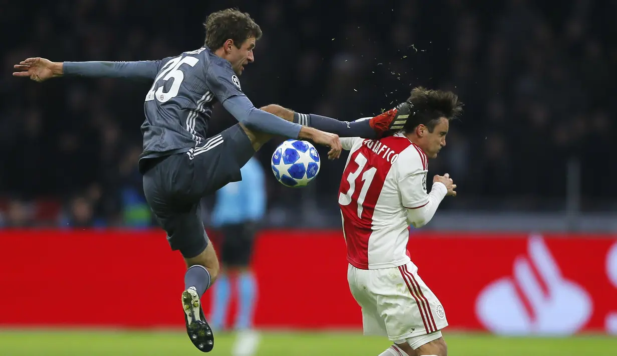 Gelandang Bayern Munchen, Thomas Mueller, menendang kepala bek Ajax Amsterdam, Nicolas Tagliafico, pada laga Liga Champions di Johan Cruyff Arena, Amsterdam, Rabu (12/12). Kedua tim bermain imbang 3-3. (AP/Peter Dejong)