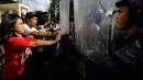 Para pengunjuk rasa saling dorong dengan polisi anti huru-hara saat menggelar aksi di dekat Kedutaan Besar AS di Manila, Filipina (11/11). Bentrokan terjadi akibat massa nekat menerobos masuk ke kantor Kedubes AS. (AP Photo/Aaron Favila)