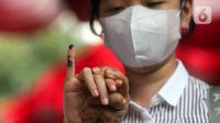 Warga menunjukkan ujung jarinya yang berlumur tinta usai melakukan pencoblosan surat suata saat simulasi pemungutan suara Pemilu 2024 di Halaman Kantor Wali Kota Jakarta Pusat, Rabu (17/1/2024). (Liputan6.com/Herman Zakharia)