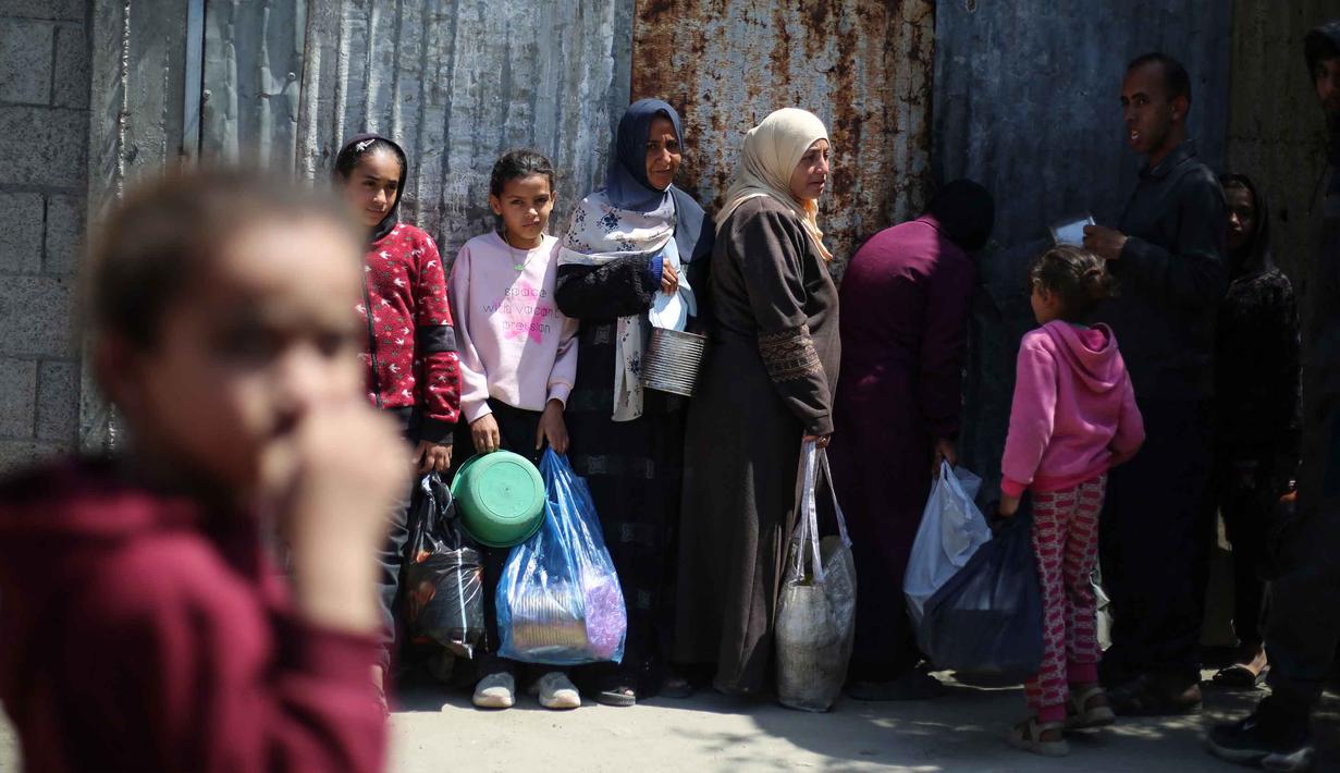 Kesenjangan antara kebutuhan dan pasokan kian melebar. Tampak dalam foto, para pengungsi Palestina menunggu untuk menerima makanan dari dapur amal di kamp pengungsi Nuseirat, Jalur Gaza Tengah pada 13 April 2026. (Eyad Baba/AFP)