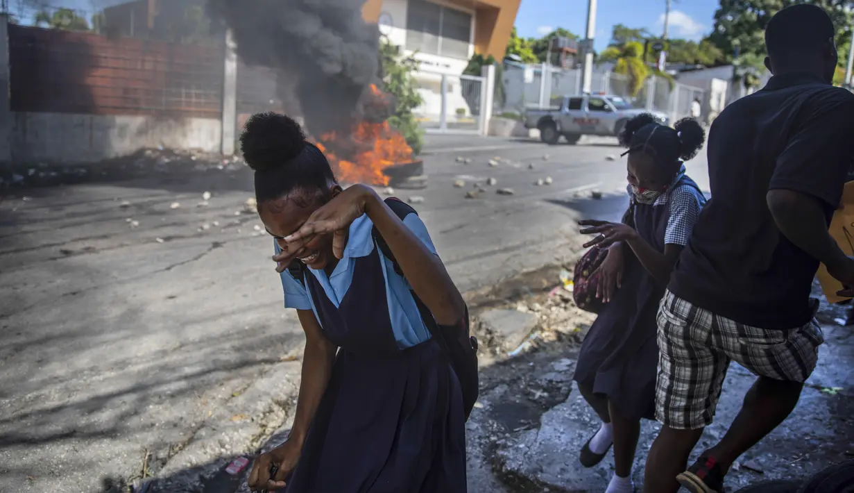 Pelajar berlari melewati barikade yang dibakar pengunjuk rasa saat protes menuntut pembebasan orang-orang yang diculik di Port-au-Prince, Haiti, 25 November 2021. Haiti mengalami peningkatan kasus penculikan terkait geng dan banyak yang menuntut uang tebusan. (AP Photo/Odelyn Joseph)