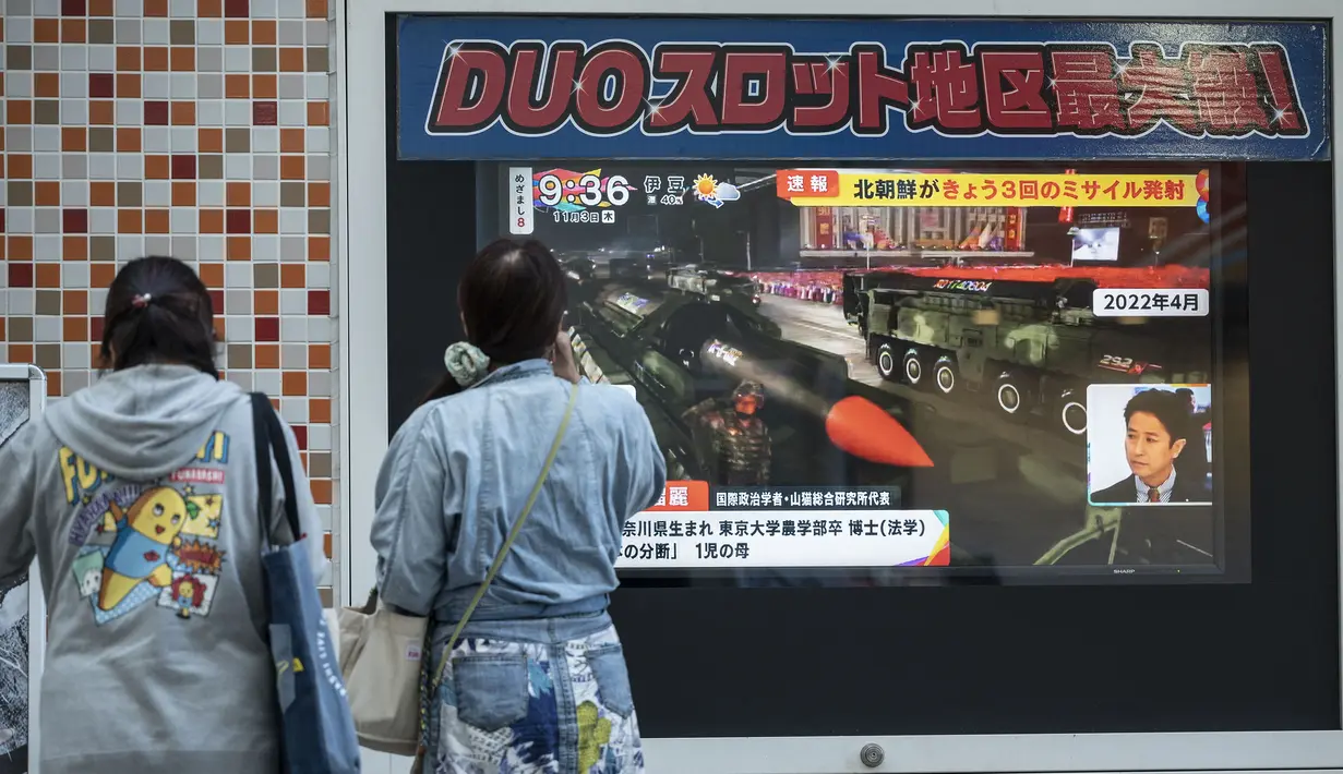 Orang-orang menonton layar televisi yang menampilkan laporan berita tentang peluncuran rudal terbaru Korea Utara dengan gambar Kim Jong Un, di sepanjang jalur pejalan kaki di Tokyo, Kamis (3/11/2022). Sekitar 25 menit setelah peluncuran pertama kali dilaporkan, Penjaga Pantai Jepang mengatakan rudal itu telah jatuh ke Samudra Pasifik. (Richard A. Brooks / AFP)