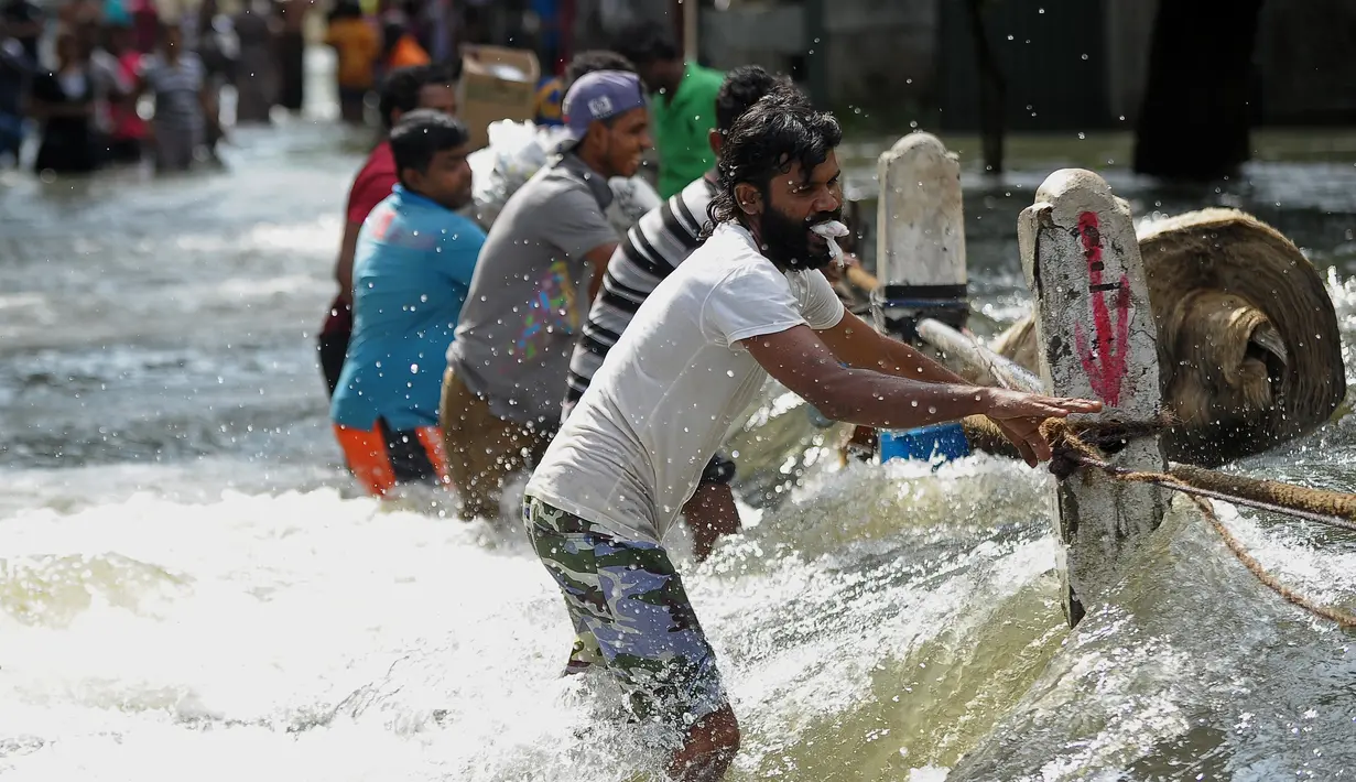 Sejumlah warga berusaha melewati banjir yang melanda kawasan pemukiman mereka di Kelaniya, Kolombo (22/5/2016). Dikabarkan sekitar 80 orang tewas akibat hujan dan tanah longsor yang melanda Sri Lanka. (AFP Photo/Ishara S Kodikara)