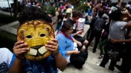 Seorang anak mengenakan topeng Cowardly Lion dari “The Wizard of Oz” lengkap dengan filter khusus dibagian lubang matanya saat menikmati gerhana matahari di Mexico City, Senin (21/8). (Rebecca Blackwell/AP)