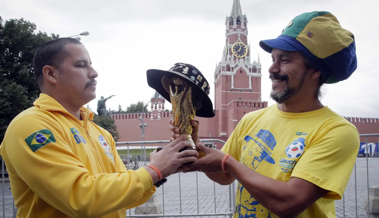 Dua suporter Brasil foto bersama miniatur trofi Piala Dunia saat berada di Kremlin, Moskow, Senin (11/6/2018). Jelang Piala Dunia, para suporter mulai berdatangan ke Rusia. (AP/Dmitri Lovetsky)