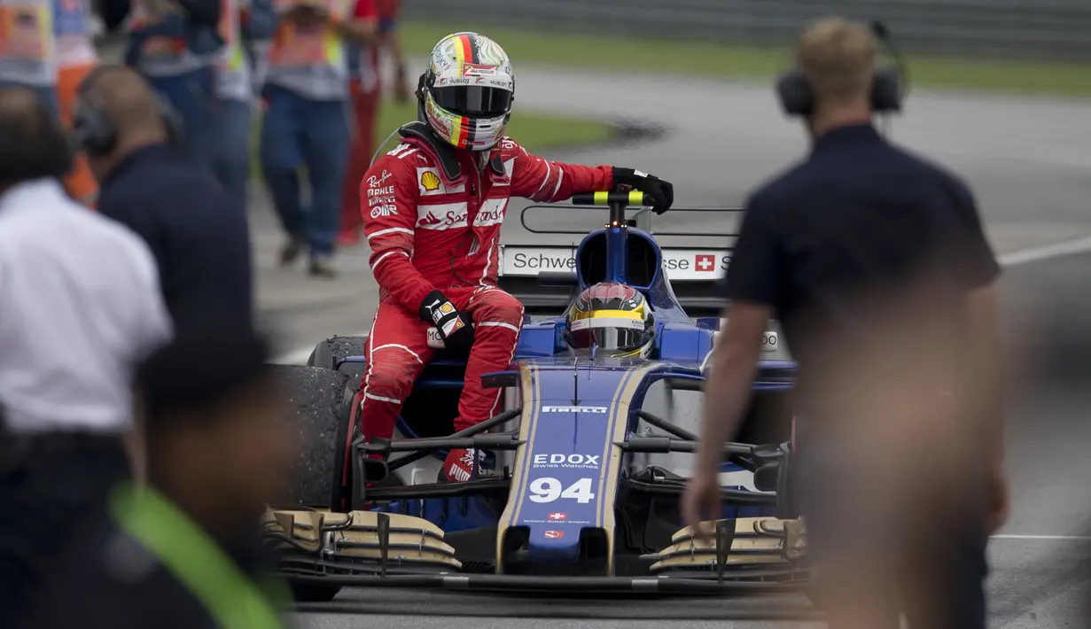 Pebalap Ferrari, Sebastian Vettel tiba di pit saat menumpang mobil Pascal Wehrlein pada balapan Formula One Malaysia Grand Prix, Sepang, (01/10/2017). Vettel akhirnya finis pada posisi keempat.  (AP/Thomas Lam)