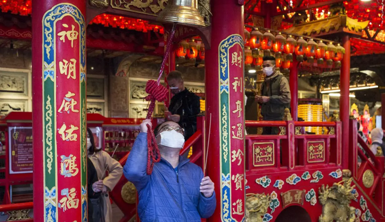 Seorang pria membunyikan lonceng keberuntungan di Kuil Hongludi Nanshan Fude untuk menandai hari ketiga Tahun Baru Imlek di New Taipei City, Taiwan, Selasa (24/1/2023). (Sam Yeh/AFP)