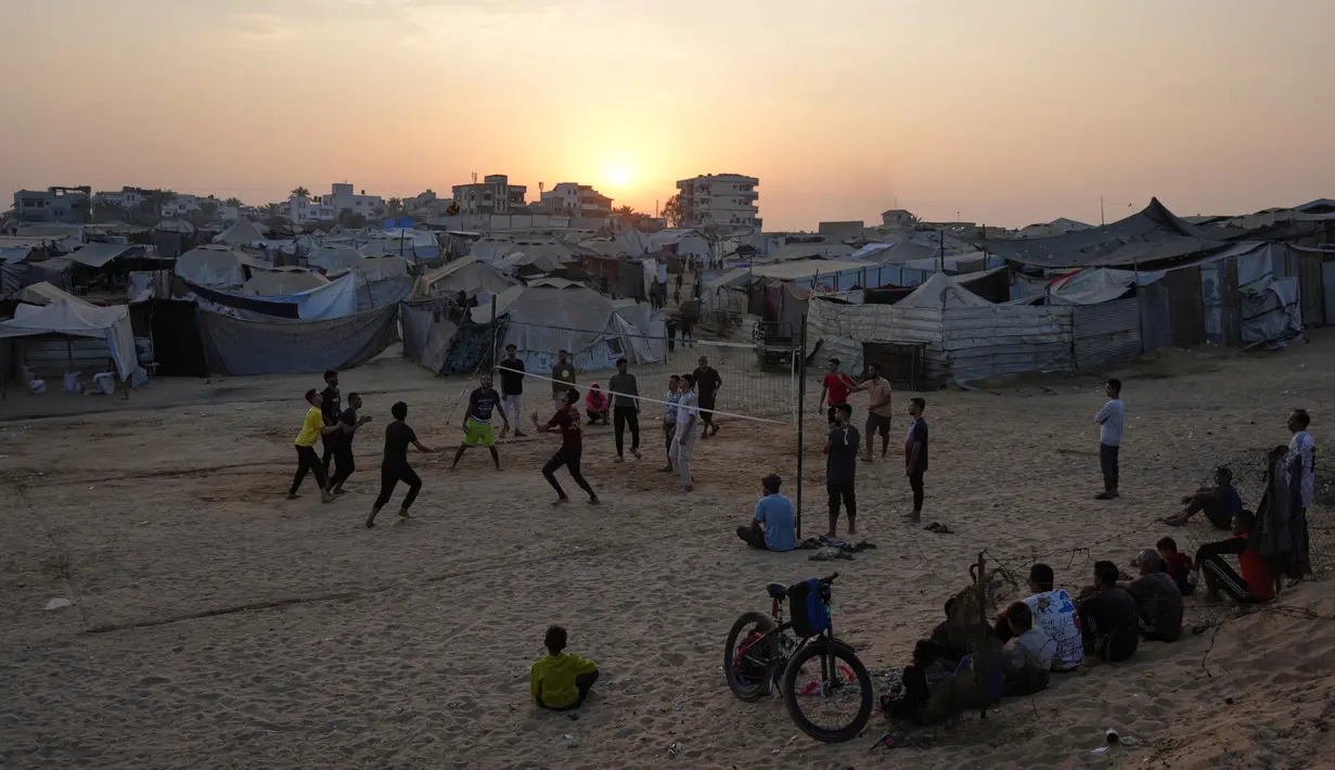 Anak-anak muda Palestina bermain voli di kamp tenda pengungsian di Zawayda, Jalur Gaza tengah, Selasa 4 November 2025. Perang yang berlangsung selama dua tahun lebih, sejak pada 7 Oktober 2023, telah menghancurkan 81% bangunan di Gaza, termasuk rumah sakit, sekolah, tempat penampungan, dan fasilitas penting lainnya. (AP Photo/Abdel Kareem Hana)
