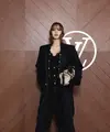 Lisa Blackpink hadir dengan gaya serba hitam mengenakan coat panjang dengan inner jumpsuit berkancing gold dipadukan kalung panjang tanpa liontin dan sepatu boots heels hitam. Ia membawa handbag warna coklat. [dok. Louis Vuitton]