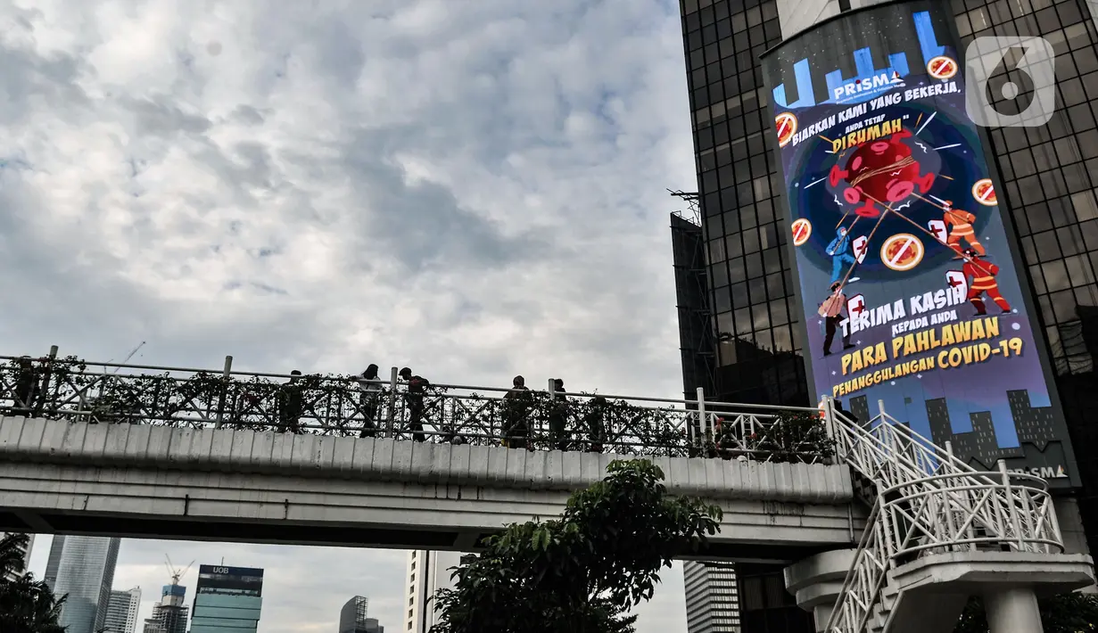 Warga berfoto di jembatan penyeberangan orang (JPO) tanpa atap di kawasan Sudirman, Jakarta, Minggu (4/4/2021). JPO tanpa atap masih menjadi wisata alternatif warga ibu kota dalam menghabiskan waktu akhir pekan untuk berfoto-foto dengan latar belakang gedung perkantoran (merdeka.com/Iqbal S Nugorho