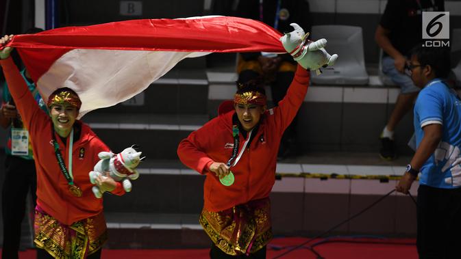 Pasangan pesilat Indonesia peraih medali emas, Ayu Sidan Wilantari dan Ni Made Dwiyanti membentangkan bendera merah putih usai penyerahan medali nomor seni ganda putri di Padepokan Pencak Silat TMII, Jakarta, Rabu (29/8). (Merdeka.com/Imam Buhori)