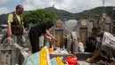 Sejumlah warga memberi persembahan  di makam kerabat selama festival Qingming di pemakaman di Hong Kong (5/4). Biasanya warga cenderung membuat persembahan untuk keluarga atau kerabat mereka agar tetap nyaman di akhirat. (AFP Photo/Isaac Lawrence)