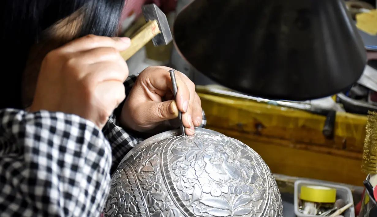 Seorang pekerja mengukir pola pada potongan perkakas emas dan perak di sebuah bengkel kerja di Kota Baimasi di Distrik Luolong, Luoyang, Provinsi Henan, China tengah (11/11/2020). (Xinhua/Han Chaoyang)