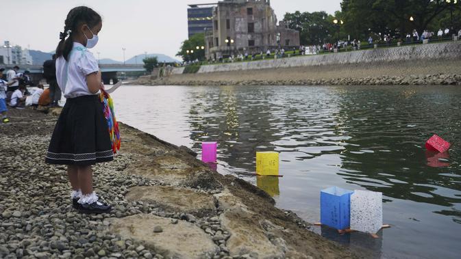 Saki Morioki, 5 tahun, menyaksikan lampion kertas melayang di sepanjang Sungai Motoyasu di depan Kubah Bom Atom di Hiroshima, Jepang barat, Kamis (6/8/2020). (AP Photo/Eugene Hoshiko)