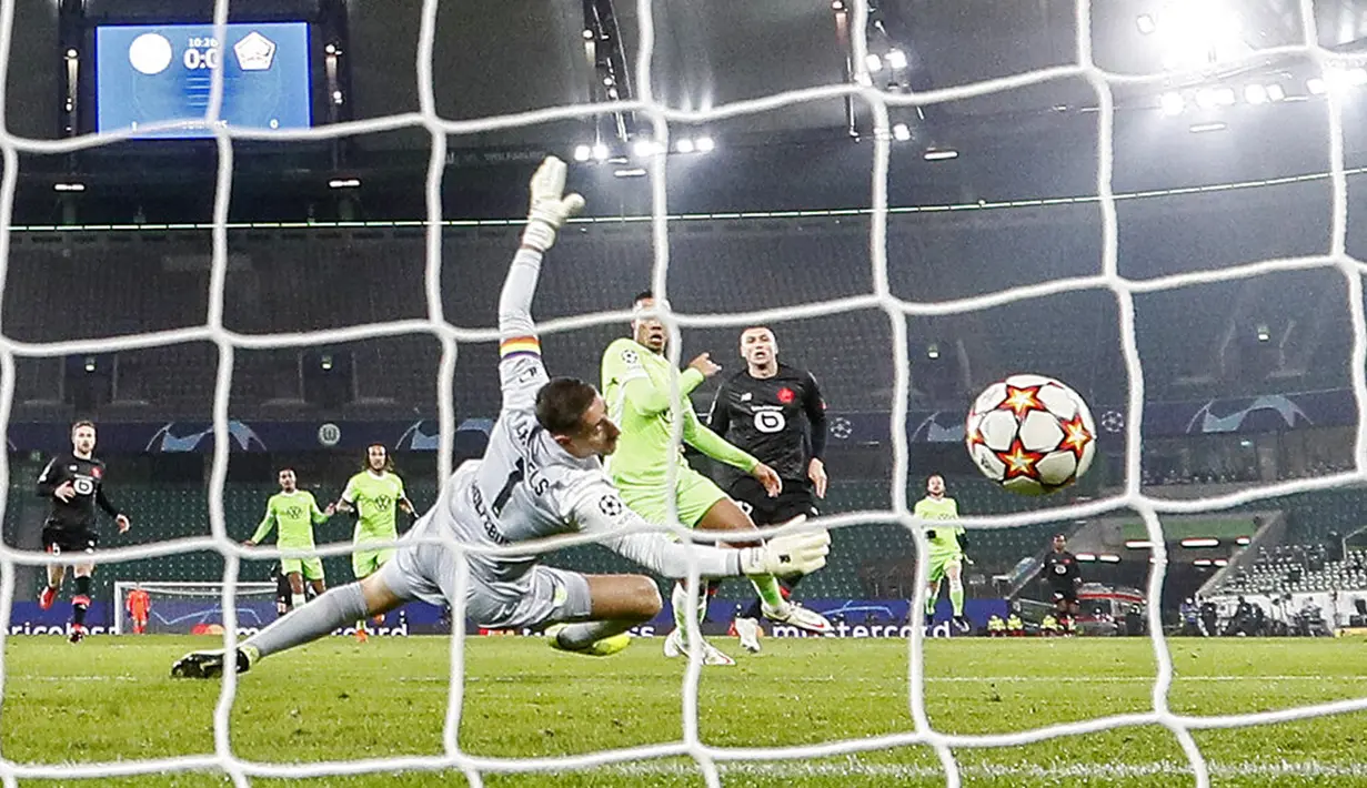 Pemain Lille Burak Yilmaz (kanan) mencetak gol ke gawang Wolfsburg yang dijaga kiper Koen Casteels pada pertandingan sepak bola Grup G Liga Champions di Wolfsburg, Jerman, 8 Desember 2021. Lille menang 3-1. (AP Photo/Martin Meissner)