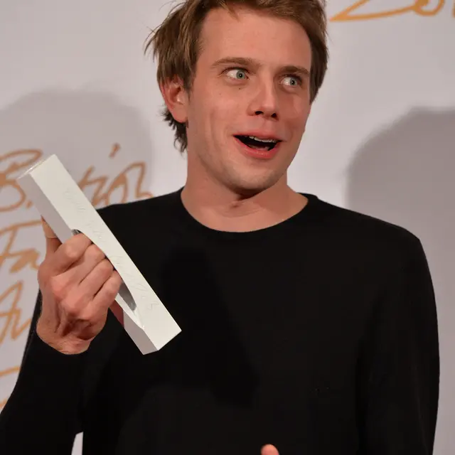 Jonathan W Anderson berpose dengan trofinya setelah memenangkan penghargaan New Establishment Designer of the Year di British Fashion Awards di London pada 2 Desember 2013. (FOTO AFP / BEN STANSALL)