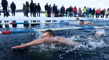 Peserta saat mengikuti kompetisi renang musim dingin tahunan dengan air es beku di Trakai, Lituania (24/2). Para peserta tetap antusias mengikuti lomba walaupun dengan suhu di luar hingga minus 12 derajat Celcius. (AFP Photo/Petras Malukas)