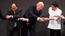 Presiden AS, Donald Trump menjabat tangan PM Vietnam, Nguyen Xian Phuc dan Presiden Filipina, Rodrigo Duterte saat salaman khas ASEAN di upacara pembukaan KTT ASEAN, Manila, Senin (13/11).Trump tampak kesulitan menempatkan tangannya. (AP/Andrew Harnik)