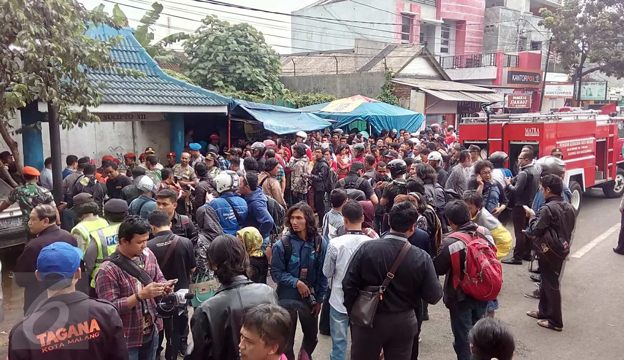 Warga dan petugas berkerumun tidak jauh dari lokasi kejadian jatuhnya pesawat Super Tucano di kawasan Jalan LA Sucipto Kota Malang, Jawa Timur, (10/2). Pesawat milik TNI AU jatuh menimpa rumah warga. (Liputan6.com/Zainul Arifin)