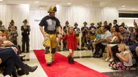 Petugas pemadam kebakaran bergaya di panggung catwalk demi menggalang dana untuk rumah sakit anak.