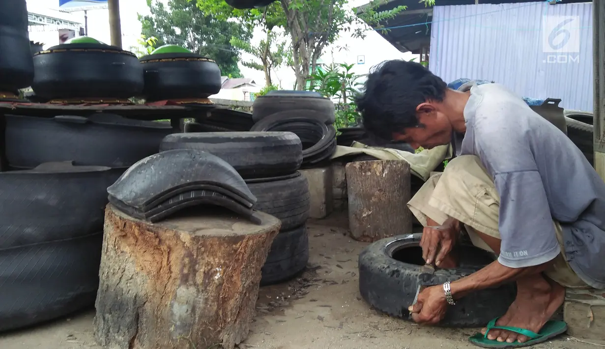 Agus Baiku mengolah ban bekas menjadi produk berkelas di Desa Pentadio Barat, Kabupaten Gorontalo, Senin (31/12). Ban mobil bekas ditempat ini diubah menjadi tempat sampah, loyang, ayunan anak-anak serta pot bunga. (Liputan6.com/Arfandi Ibrahim)