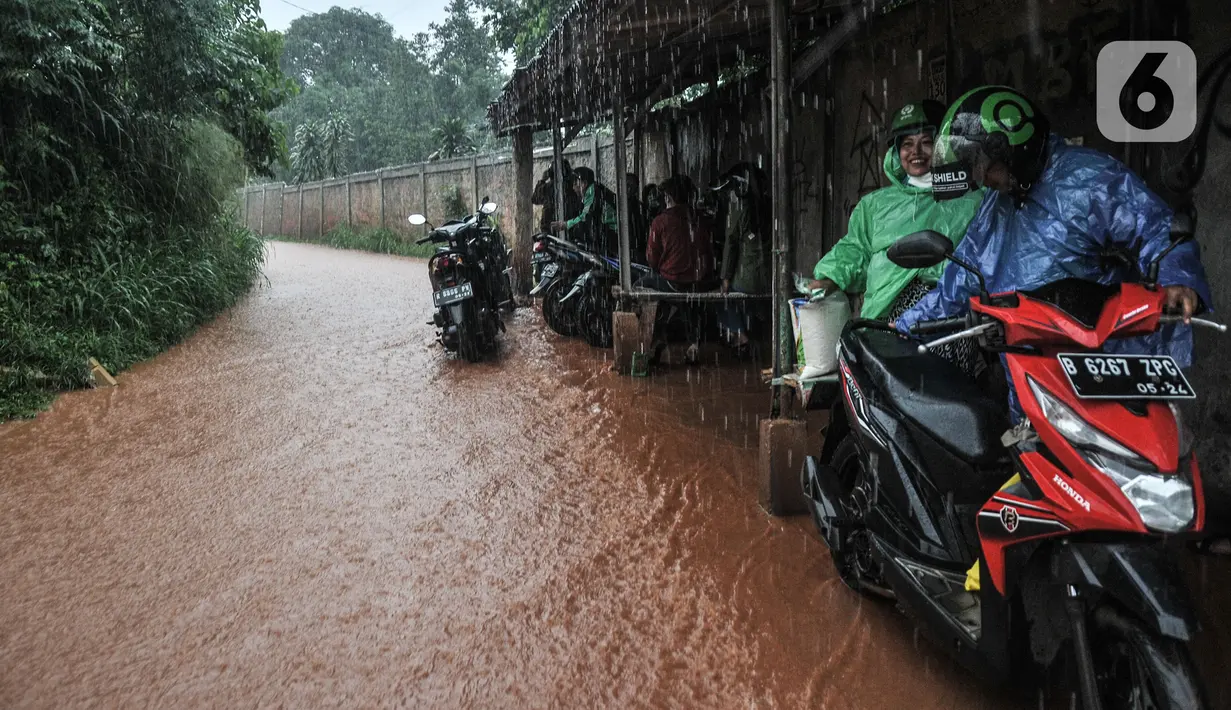 Aliran genangan lumpur yang berasal dari jalan masuk perumahan Depok Jaya Agung, Sawangan, Depok, Minggu (7/11/2021). Hujan deras yang mengguyur Depok dan sekitarnya menyebabkan Jalan Raya Sawangan  digenangi banjir lumpur dan membahyakan keselamatan pengendara. (merdeka.com/Iqbal S Nugroho)