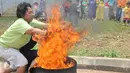 Warga dibantu petugas Damkar mencoba memadamkan api menggunakan karung basah di Rusun Jatinegara Barat, Jakarta, Senin (14/9/2015). Pelatihan dan simulasi ini guna mengantisipasi penanganan sejak dini tindak kebakaran. (Liputan6.com/Gempur M Surya)