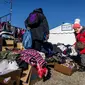 Pengungsi berusaha menemukan pakaian yang bisa digunakan setelah melintasi perbatasan Ukraina-Polandia di perbatasan Medyka, pada 17 Maret 2022. Lebih dari tiga juta warga Ukraina telah melarikan diri melintasi perbatasan, kebanyakan wanita dan anak-anak, menurut PBB. (Wojtek RADWANSKI/AFP)