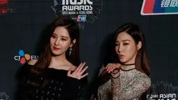 Personel girlsband Girls Generation, Tiffany (kanan) dan Seohyun berpose di karpet merah Mnet Asian Music Awards (MAMA) 2015 di Hong Kong, Rabu (2/12). Leader Girls Generation itu tampil cantik mengenakan gaun merah. (REUTERS/Bobby Yip)