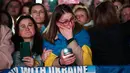 Seorang pengunjuk rasa berbalut bendera nasional Ukraina bereaksi ketika ia mengambil bagian dalam pertemuan untuk mendukung Ukraina yang menandai tahun ketiga invasi Rusia di Trafalgar Square, pusat kota London, pada 24 Februari 2025. (HENRY NICHOLLS/AFP)