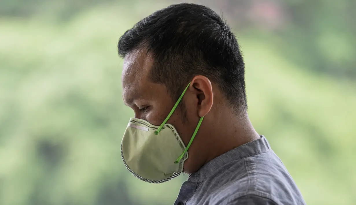 Seorang pria berjalan mengenakan masker saat kabut menyelimuti Kuala Lumpur (10/9/2019). Malaysia tengah mempersiapkan membuat hujan buatan setelah kualitas udara di sejumlah negara bagian mencapai level yang tidak sehat. (AFP Photo/Mohd Rasfan)
