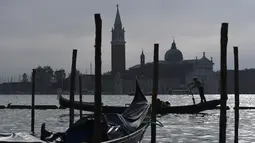 Gondola mengangkut wisatawan yang dekat dengan perairan Riva degli Schiavoni dengan latar gereja San Giorgio Maggiore di Venice (4/11/2019). Di kawasan ini ada pejalan kaki yang ramai meskipun sering penuh sesak di sepanjang tepi pantai, yang terletak di Cekungan St. Mark. (AFP Photo/Miguel Medina)