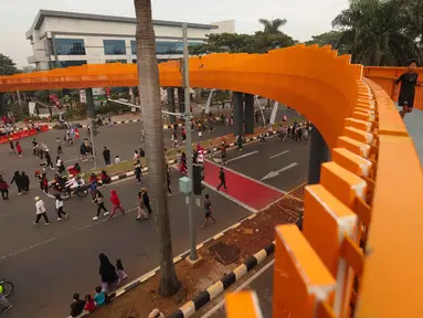Warga beraktivitas di sekitar Jembatan Penyeberangan Orang (JPO) di Jalan Tegar Beriman, Cibinong, Kabupaten Bogor, Jawa Barat, Minggu (14/6/2026). (Kapanlagi.com/Budy Santoso)
