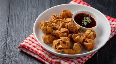 Sepiring bakso goreng keemasan yang renyah, disajikan dengan saus sambal pedas sebagai pelengkap rasa