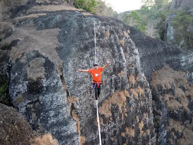Gambar pada 9 September 2019 memperlihatkan atlet olahraga ekstrem, Andi Ardi berjalan di atas tali yang menggantung di ketinggian 740 meter (2.427 kaki) di Gunung Nglanggeran, Yogyakarta. Aksi itu sebagai bagian dari kampanye pariwisata untuk mempromosikan tempat yang indah. (AGUNG SUPRIYANTO/AFP)