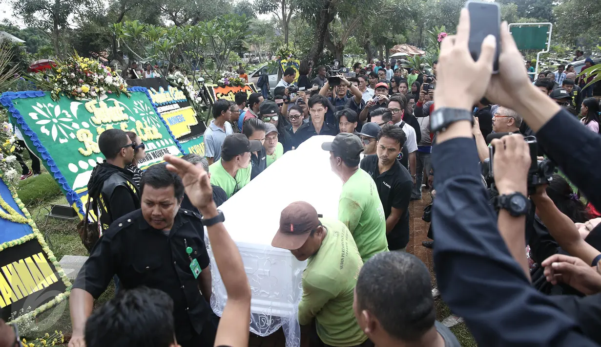 Petugas menggotong peti jenazah Mike Mohede dalam prosesi pemakaman di TPU Tanah Kusir, Jakarta, Selasa (2/8). Prosesi pemakaman Mike Mohede berjalan diiringi isak tangis keluarga, sahabat dan kekasihnya, Christina Maria. (Liputan6.com/Herman Zakharia)