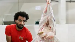 Mohammad Ibraheem saat memotong daging di sebuah rumah jagal hewan di hari ketiga Idul Adha di Kota Kuwait (13/8/2019). Karena kemiripannya dengan bintang Liverpool Mohamed Salah banyak orang meminta foto bareng dengannya. (AFP Photo/Yasser Al-Zayyat)