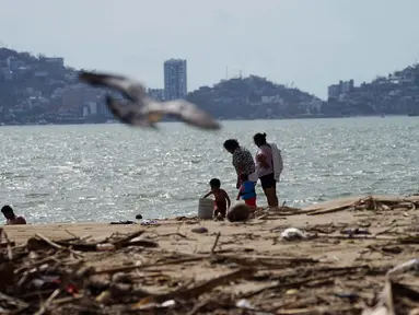 Warga setempat berjalan di pantai yang dipenuhi puing-puing setelah Badai Otis menerjang Acapulco, Meksiko, Kamis, 26 Oktober 2023. (AP Photo/Marco Ugarte)
