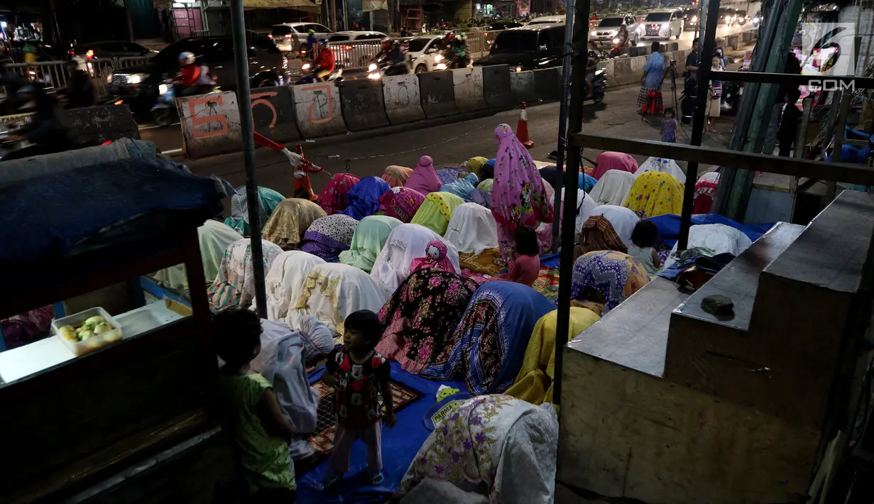 Pemandangan saat jemaah melaksanakan salat tarawih hingga ke badan jalan akibat melubernya Musala Miftahul Jannah di Kawasan Pasar Gembrong, Jakarta, Kamis (17/5). (Liputan6.com/JohanTallo)