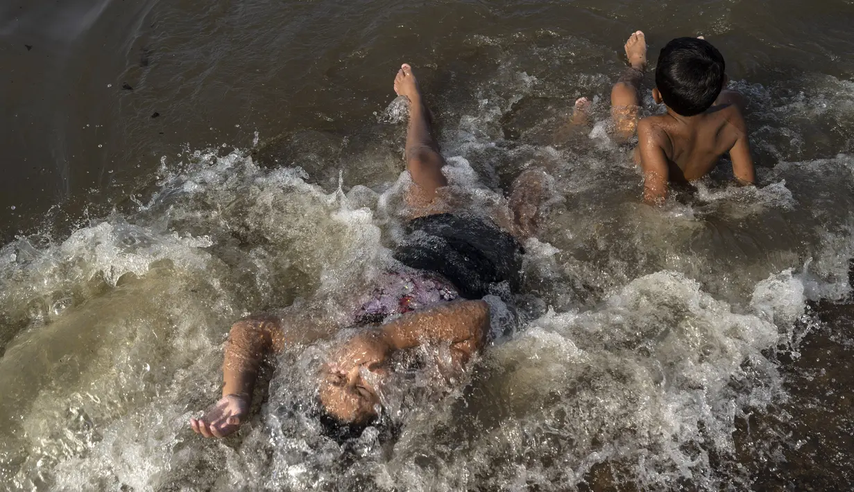 Anak-anak mandi di sungai Rio de la Plata untuk mendinginkan diri dari suhu tinggi di Buenos Aires, Argentina, Kamis, 2 Maret 2023. Gelombang panas datang di tengah-tengah pemadaman listrik  pada hari Rabu yang menyebabkan sekitar 40% keluarga di negara itu tanpa listrik selama berjam-jam. (AP Photo/Rodrigo Abd)