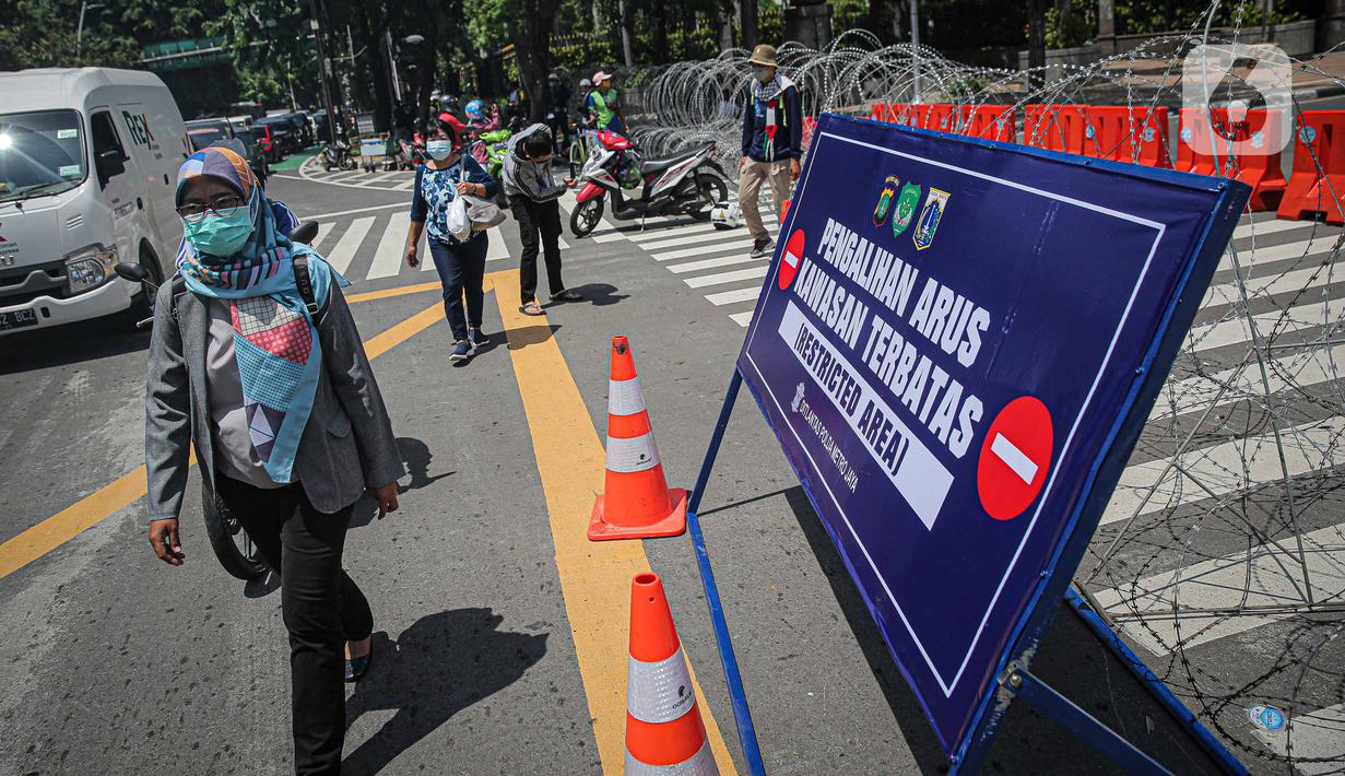 Warga berjalan dekat kawat berduri di kawasan Jalan MH Thamrin, Jakarta, Kamis (2/12/2021). Polda Metro Jaya memasang barikade di sejumlah titik menuju kawasan Patung Kuda-Monumen Nasional (Monas) Jakarta Pusat guna mengantisipasi kerumunan massa aksi Reuni 212. (Liputan6.com/Faizal Fanani)